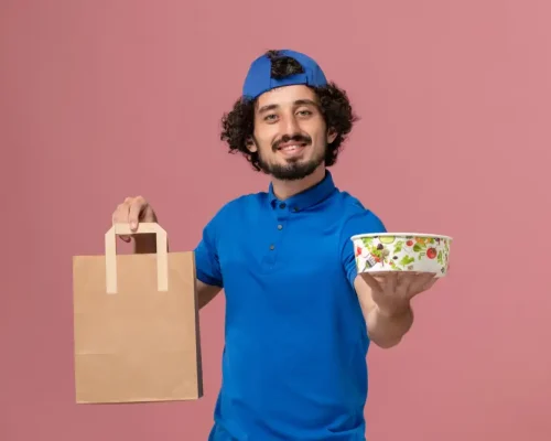 front-view-male-courier-blue-uniform-cape-holding-delivery-food-package-bowl-pink-wall-delivery-service-uniform-job front-view-male-courier-blue-uniform-cape-holding-delivery-food-package-bowl-pink-wall-delivery-service-uniform-job